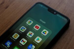 Close-up of a smartphone showing various Google apps on its screen.